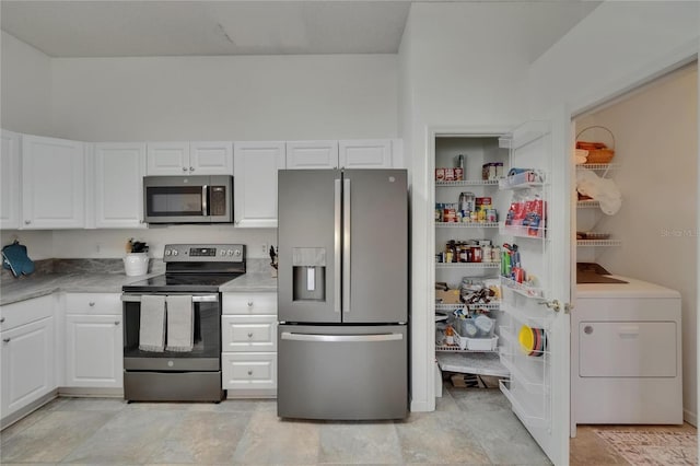 kitchen with light countertops, stainless steel appliances, washer / clothes dryer, and white cabinetry