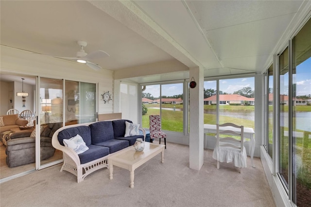 sunroom featuring carpet floors, a ceiling fan, and a water view