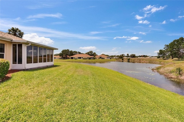 view of yard with a sunroom and a water view