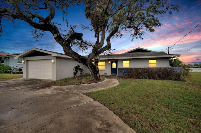 ranch-style home with driveway, an attached garage, a lawn, and stucco siding