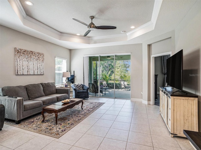 living room featuring a raised ceiling, light tile patterned floors, crown molding, a textured ceiling, and ceiling fan
