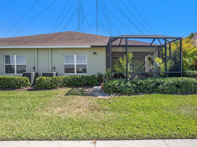 back of property with a yard, a lanai, central AC, and stucco siding
