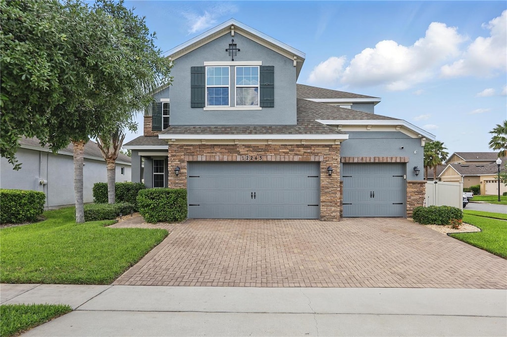 view of front of house with a shingled roof, stucco siding, a front lawn, and decorative driveway