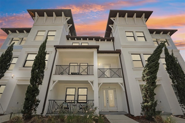 view of front of property with a porch, stucco siding, and a balcony
