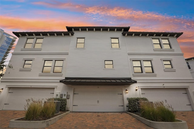 view of property with a garage, stucco siding, and decorative driveway