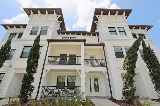 view of front of property featuring covered porch, stucco siding, and a balcony
