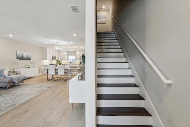 stairs with wood finished floors, visible vents, and recessed lighting
