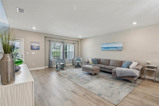 living area featuring visible vents, baseboards, light wood finished floors, and recessed lighting