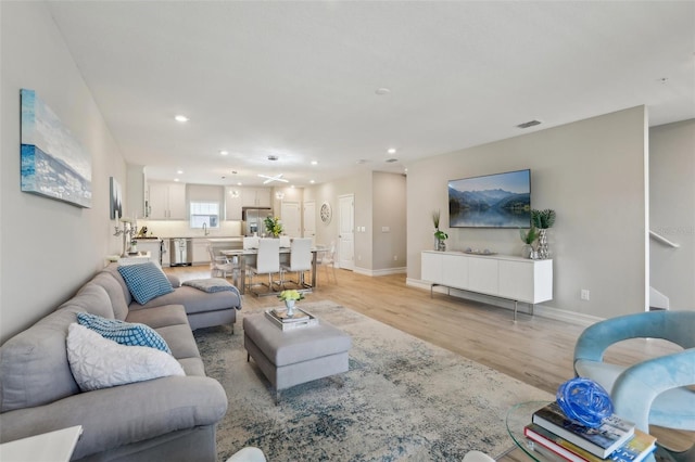 living room with visible vents, baseboards, recessed lighting, and light wood finished floors