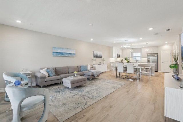 living room featuring light wood-style flooring, baseboards, visible vents, and recessed lighting