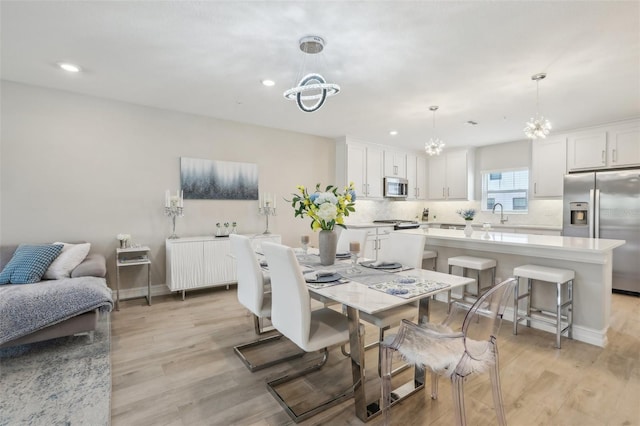 dining area with a chandelier, radiator, light wood finished floors, and recessed lighting