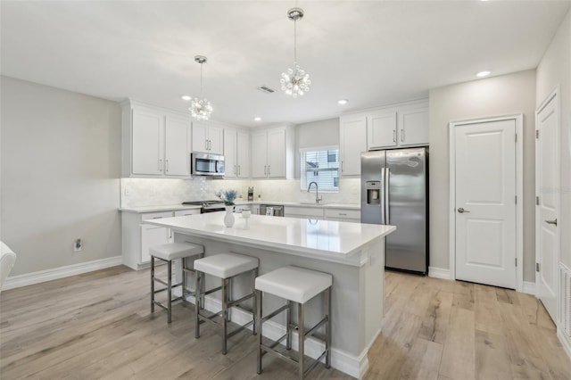 kitchen featuring a sink, light wood-type flooring, a chandelier, and stainless steel appliances
