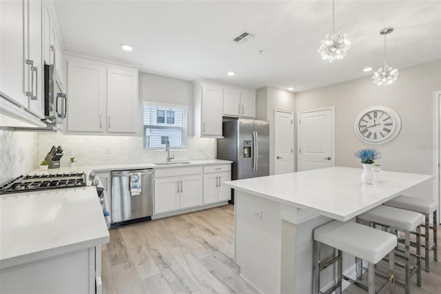 kitchen featuring light countertops, backsplash, a breakfast bar area, appliances with stainless steel finishes, and a sink