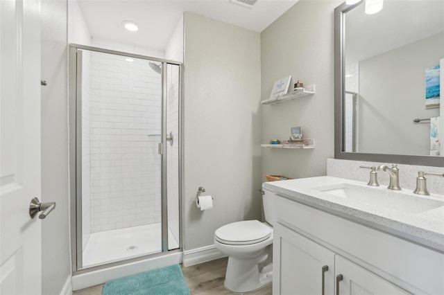 full bath featuring vanity, baseboards, toilet, a shower stall, and wood finished floors
