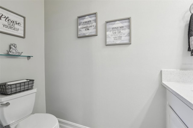 half bathroom with vanity, baseboards, and toilet