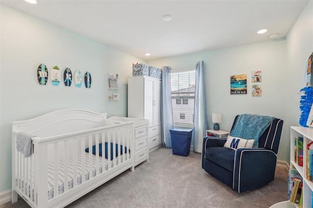 bedroom with recessed lighting, light colored carpet, and a nursery area