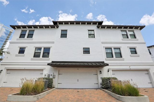 townhome / multi-family property with decorative driveway, a garage, and stucco siding