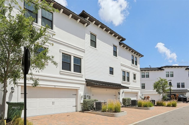 view of front facade featuring stucco siding, decorative driveway, and an attached garage