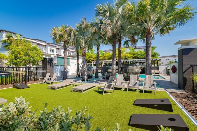 view of property's community featuring a pool, fence, and a lawn