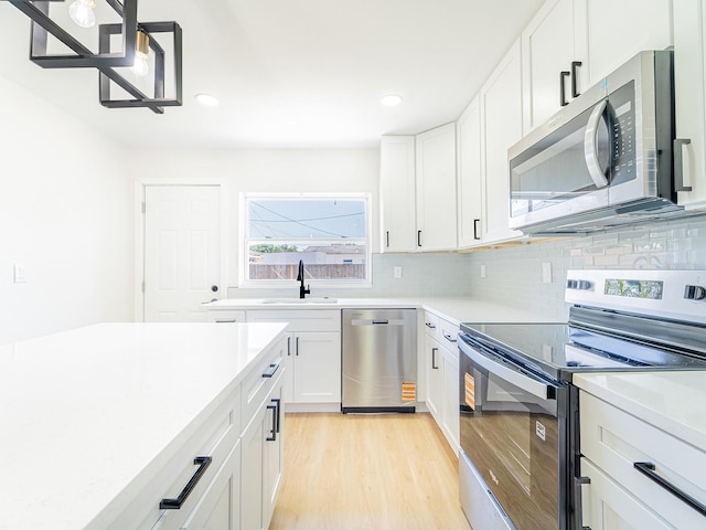 kitchen featuring tasteful backsplash, a sink, light wood-type flooring, stainless steel appliances, and light countertops