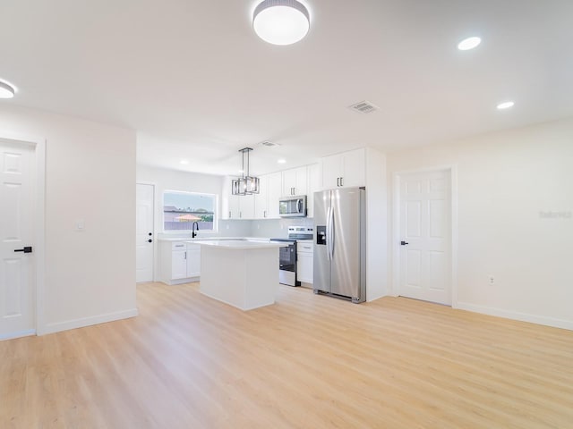 kitchen featuring white cabinets, stainless steel appliances, visible vents, and light wood-style floors