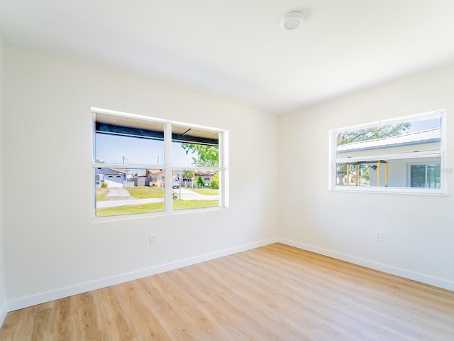 spare room with baseboards and wood finished floors