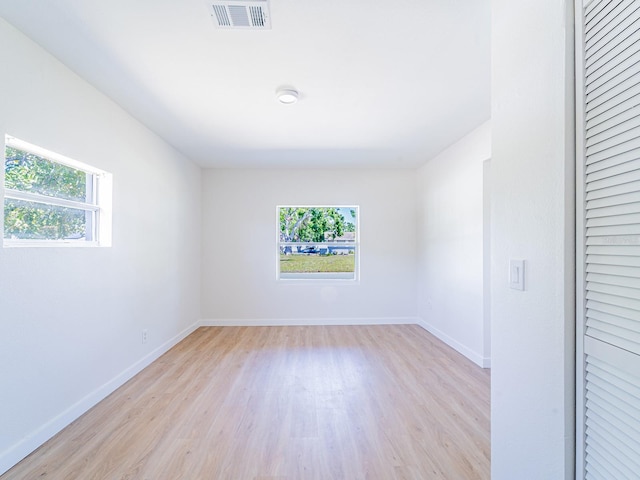 empty room featuring visible vents, light wood-style flooring, and plenty of natural light