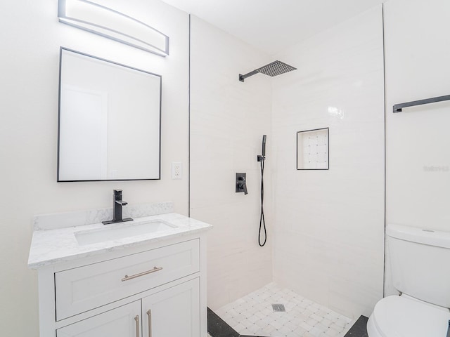 bathroom with tiled shower, vanity, and toilet