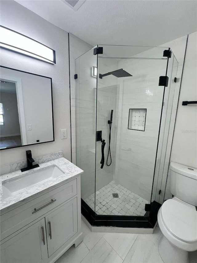 bathroom with toilet, vanity, marble finish floor, and a stall shower
