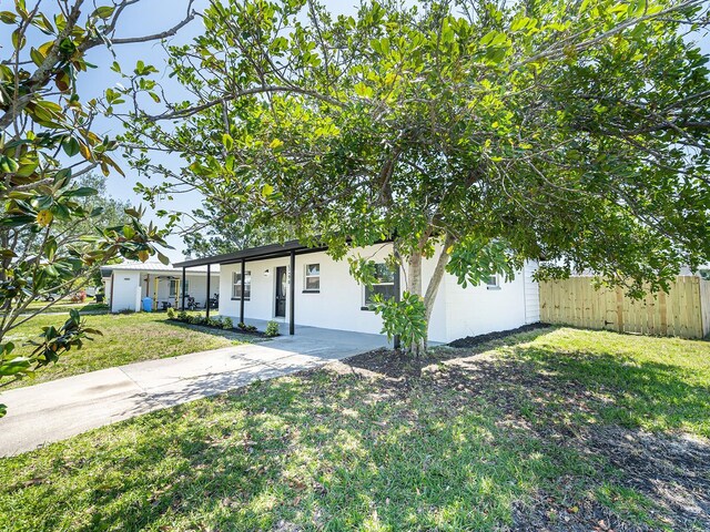 view of front of house featuring driveway, a front yard, fence, and stucco siding
