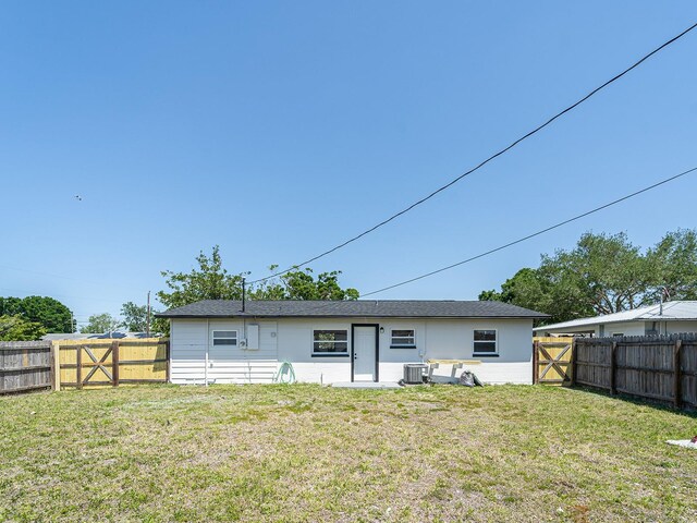 rear view of house featuring a fenced backyard, a gate, and a lawn