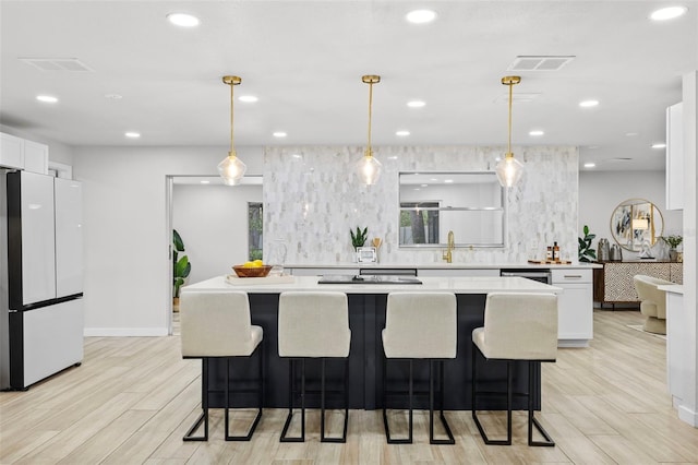 1905 Oro Ct, Clearwater, FL 33764 - kitchen with light countertops, freestanding refrigerator, a kitchen island, white cabinets, and visible vents