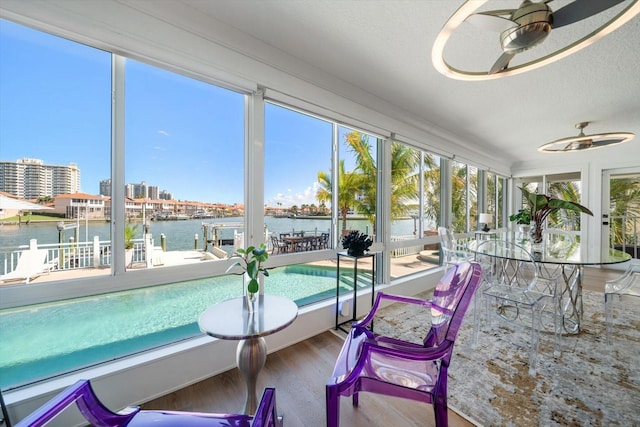 sunroom / solarium featuring a water view and wood finished floors