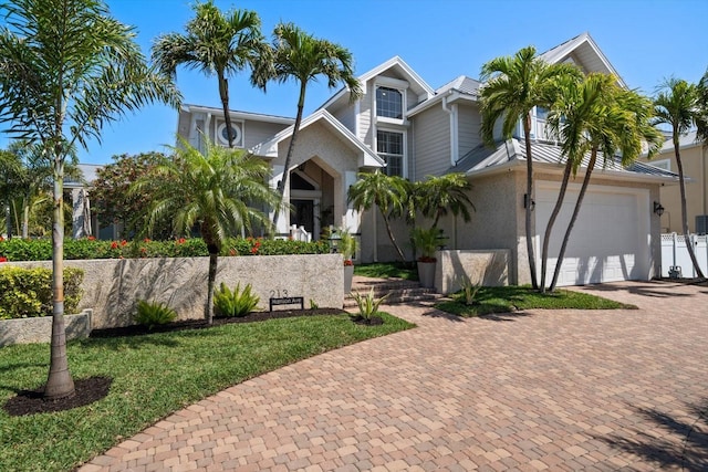 view of front facade with fence, a balcony, decorative driveway, and an attached garage