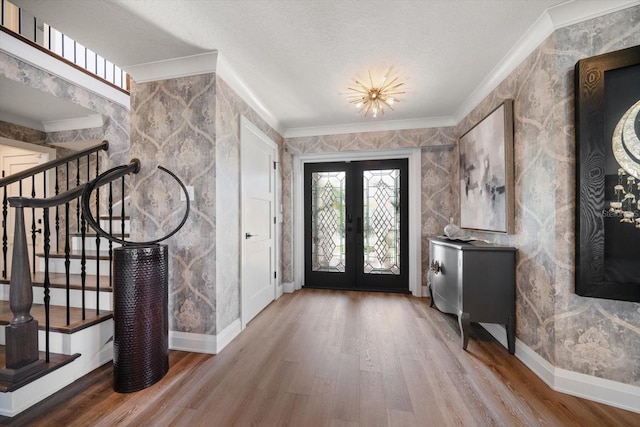 foyer featuring stairs, french doors, crown molding, and wood finished floors