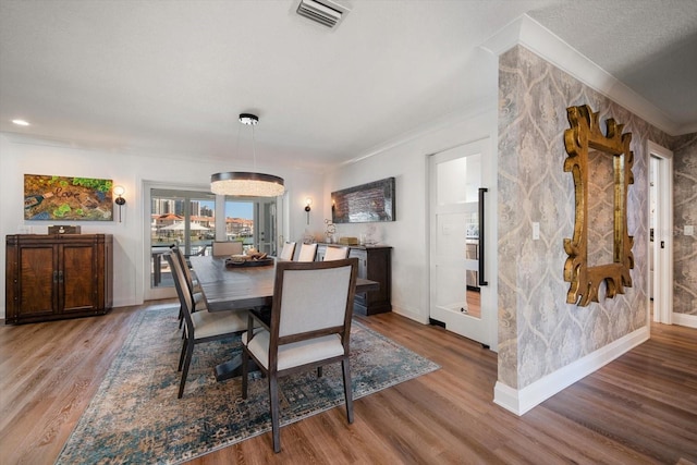 dining space with crown molding, visible vents, baseboards, and wood finished floors