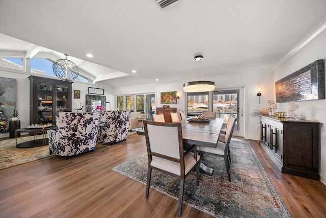 dining room with an inviting chandelier, recessed lighting, visible vents, lofted ceiling, and wood finished floors