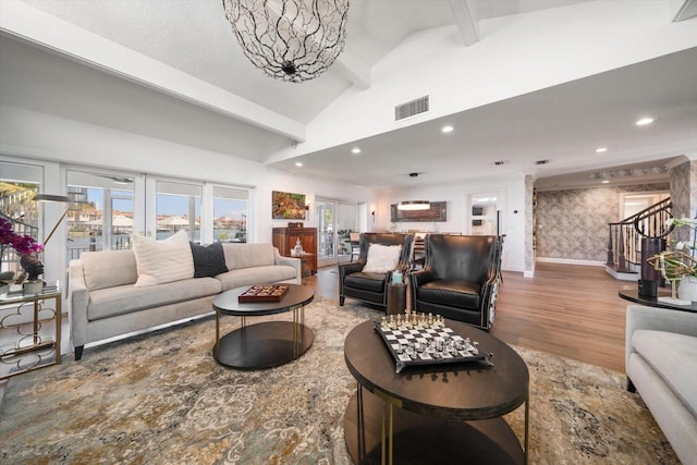 living room featuring visible vents, baseboards, wallpapered walls, wood finished floors, and stairs