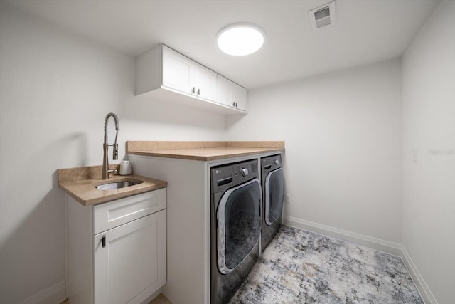washroom with visible vents, washing machine and clothes dryer, a sink, baseboards, and cabinet space