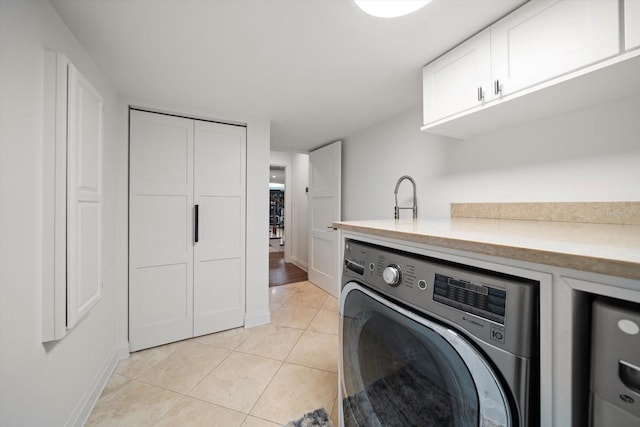 clothes washing area with light tile patterned floors, washer / dryer, baseboards, and cabinet space