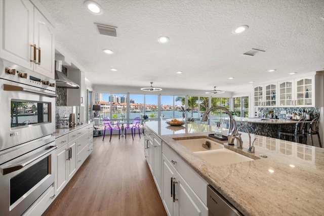 kitchen featuring a sink, visible vents, a textured ceiling, and stainless steel double oven
