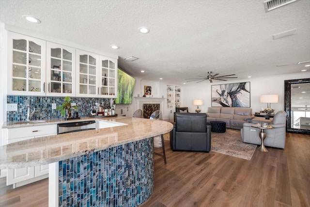 bar with wet bar, a textured ceiling, visible vents, ceiling fan, and dishwasher
