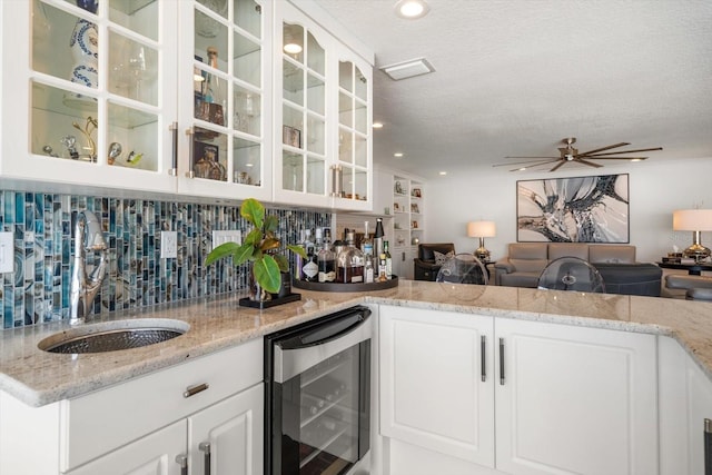 bar featuring indoor wet bar, a sink, a ceiling fan, decorative backsplash, and beverage cooler
