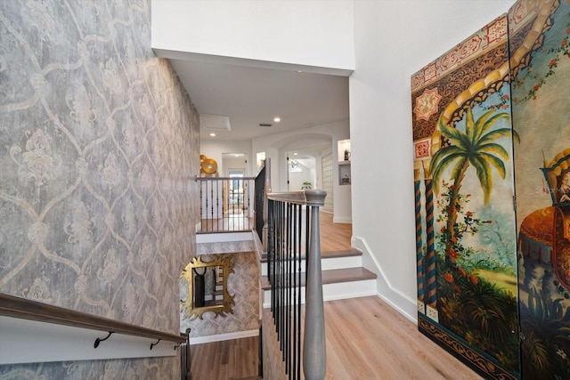 interior space featuring arched walkways, baseboards, and wood finished floors