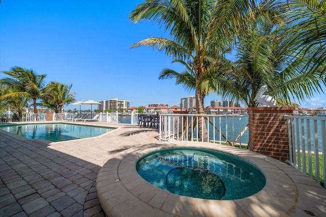 view of pool with a patio area, a fenced in pool, an in ground hot tub, and a water view