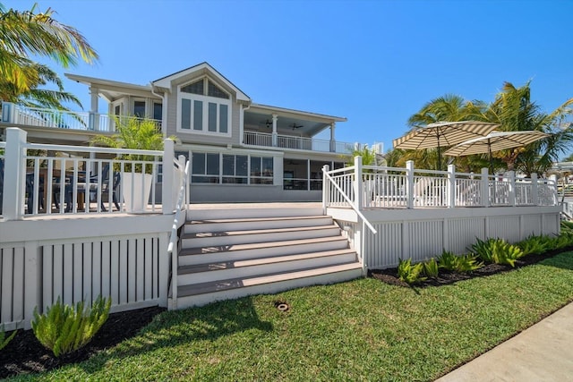 rear view of house featuring a yard, a balcony, a deck, and stairway