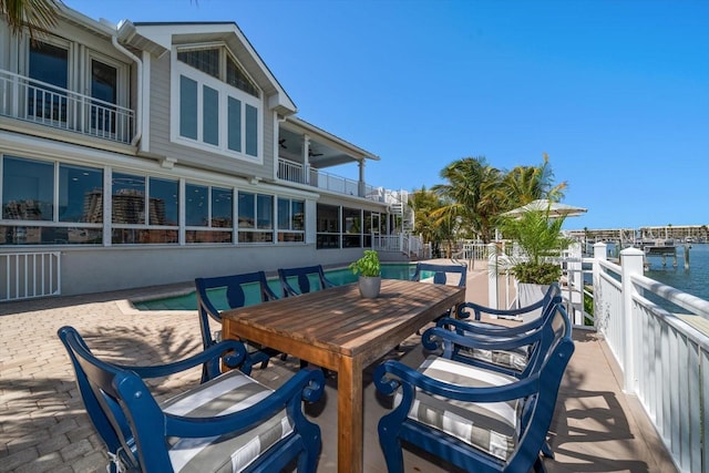 view of patio with a water view, ceiling fan, outdoor dining space, and a balcony