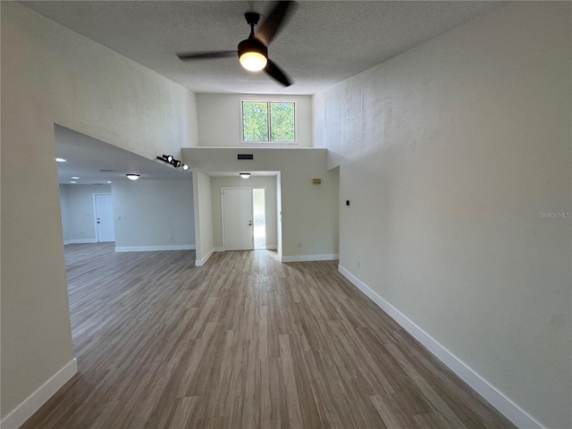 3924 Orchard Hill Cir, Palm Harbor, FL 34684 - unfurnished living room featuring visible vents, baseboards, a ceiling fan, wood finished floors, and a towering ceiling
