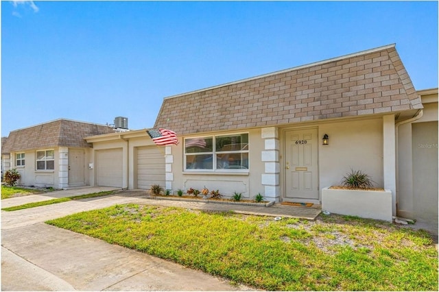 6920 Lafayette N Unit 6920, Pinellas Park, FL 33781 - view of front facade with mansard roof, a garage, concrete driveway, stucco siding, and roof with shingles
