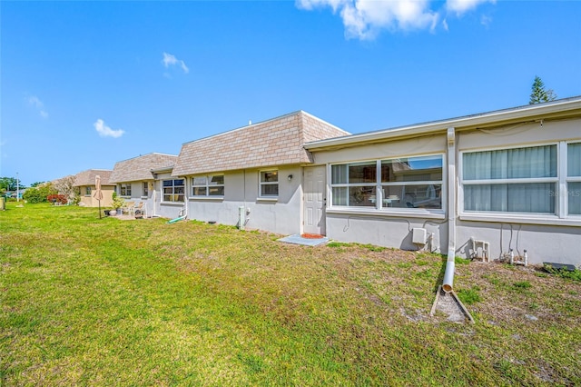 6920 Lafayette N Unit 6920, Pinellas Park, FL 33781 - back of house featuring a lawn, a shingled roof, stucco siding, and mansard roof